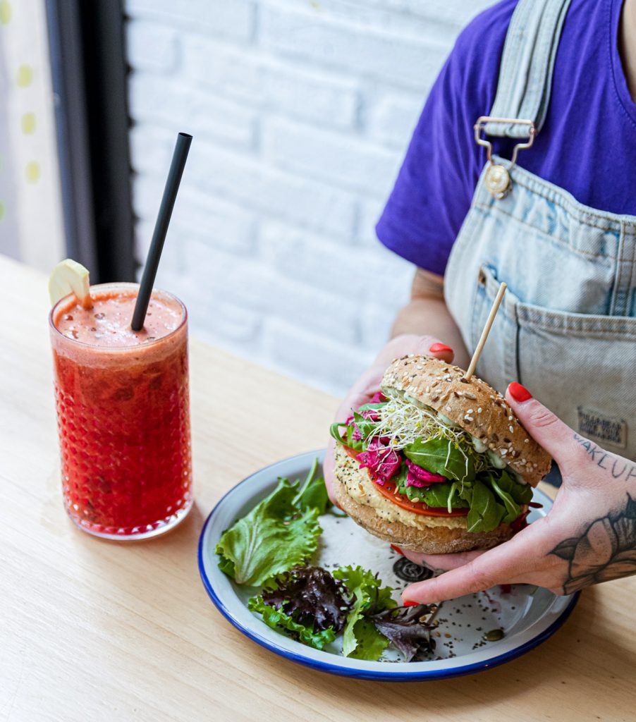 imagen de persona comiendo hamburguesa vegana para qué ofrece la carta de un restaurante vegano en otoño en españa